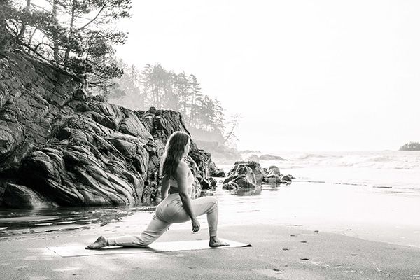 Laura, founder of Tofino Breath and Mediation, stretching on mat by the beach