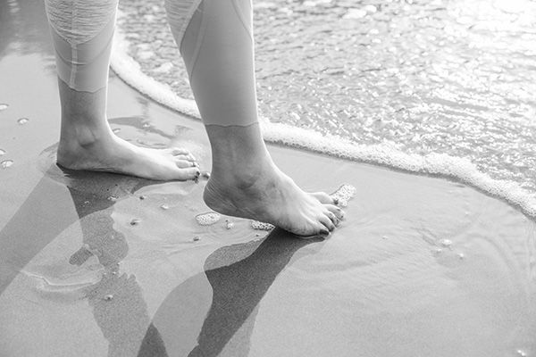 Laura's feet on the sand by the ocean