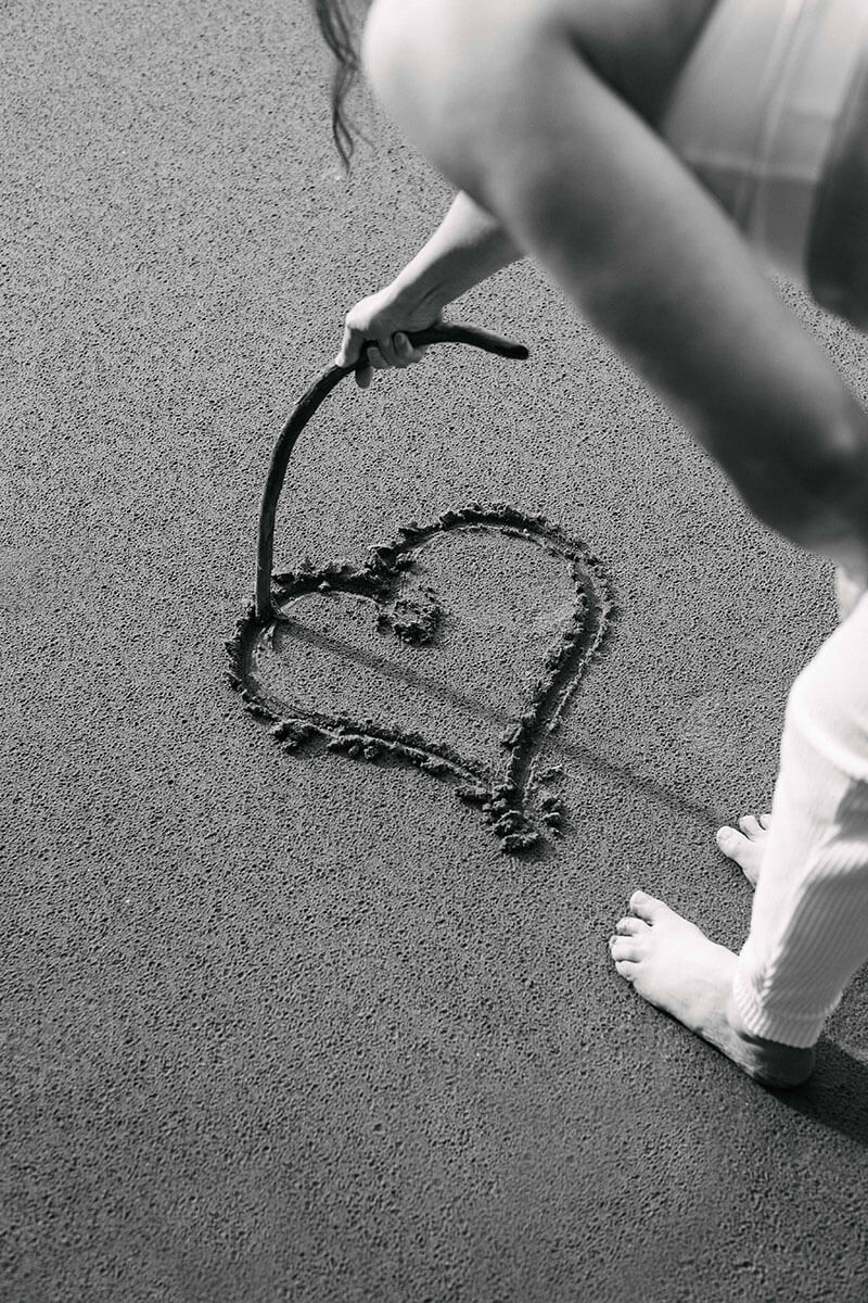 Laura drawing a heart in the sand 