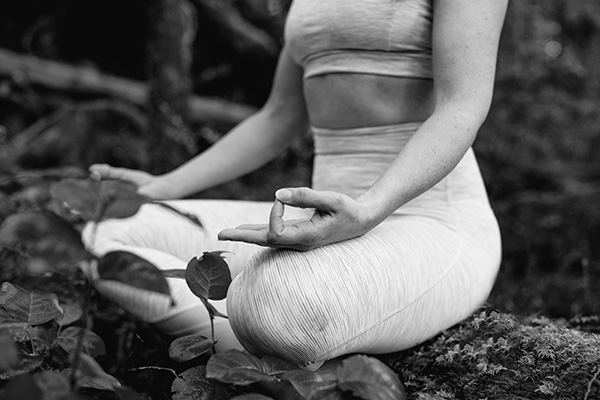 Laura meditating on log in the forest